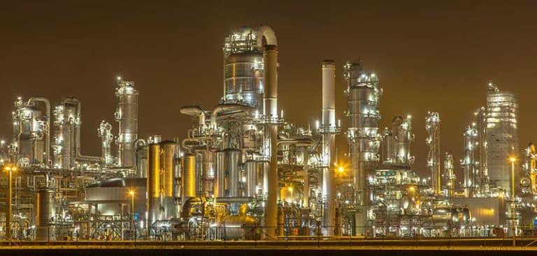 Oil, gas, and chemical process safety—industrial facility at night with hazard reviews, compliance, and risk management solutions.