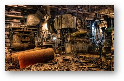Industrial facility interior showing combustible dust accumulation and equipment hazards.