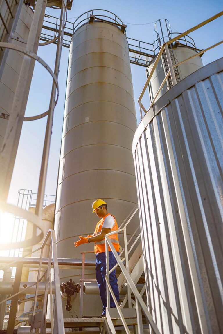 Engineer in safety vest and helmet inspecting equipment at an industrial facility for hazardous area classification